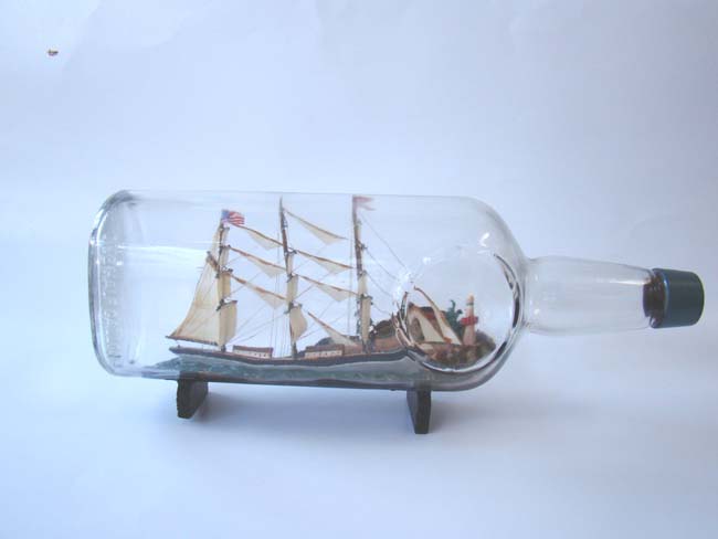 A large Ship in a bottle, the background featuring a coastal town with trees and a lighthouse, American circa 1940